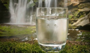 стакан воды на фоне водопада